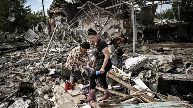 امرأتان تبحثان عن ما يمكن انقاذه من محتويات منزلهن الذي انهار بعد غارة جوية روسية