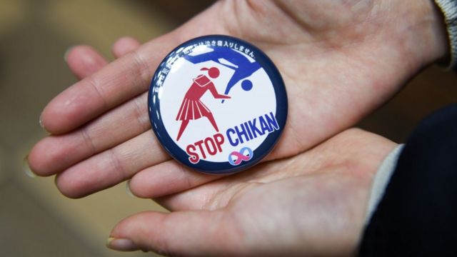 Una imagen de una insignia que dice "Stop Chikan" con una ilustración que muestra a una mujer que parece arrojar al suelo a un atacante masculino