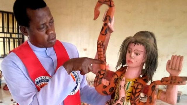 Reverend Paul Obayi holds an idol