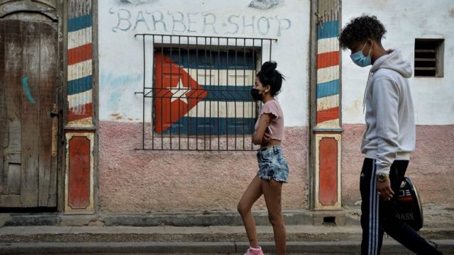 Dos personas caminando en una calle cubana.