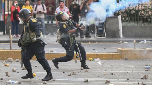 Um policial lança gás lacrimogêneo