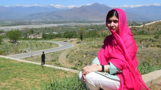 Malala Yousafzai, sentada em frente &agrave; paisagem de sua terra natal