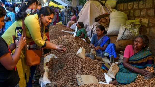 Mulher compra amendoim em feira livre na Índia