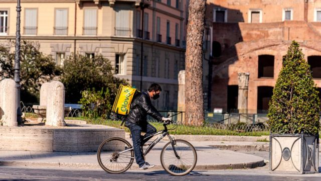 A food delivery man rides his bicycle in Rome