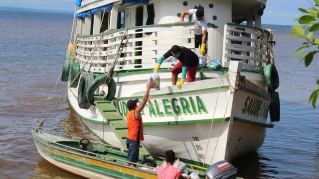 Tripulação de barco transfere kits de limpeza e alimento para embarcação menor