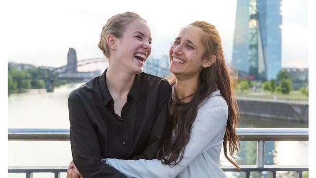 Duas mulheres abraçadas rindo