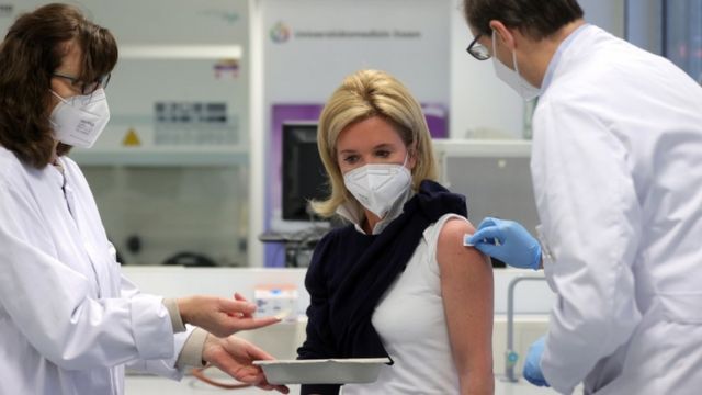 A medical professional is vaccinated against Covid-19 with Moderna's vaccine at the University Hospital in Essen, Germany