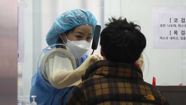A medical professional takes samples from people at a testing centre in Seoul