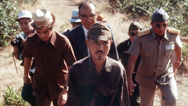 Lieutenant Hiroo Onoda walks from the jungle with a group behind him