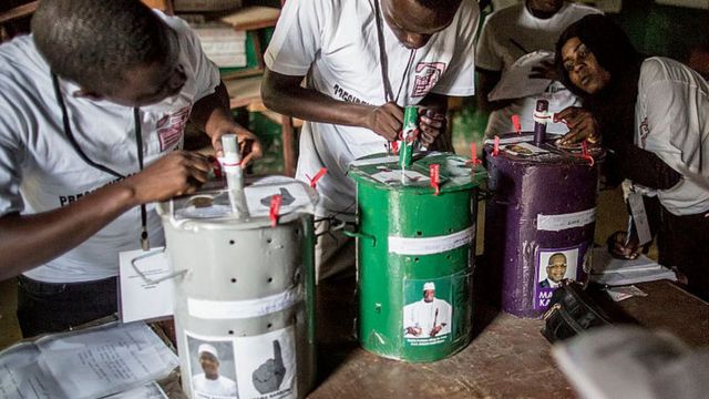 Des membres du personnel électoral vérifient les scellés des fûts dans un bureau de vote à Banjul, le 1er décembre 2016.