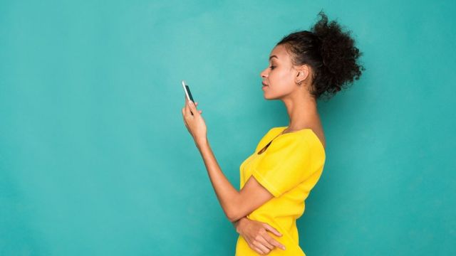 Young woman on holding a phone in her hand, on a turquoise background
