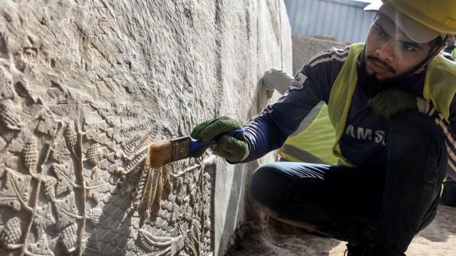 أحد عمال الآثار ينظف منحوتة عثر عليها.
