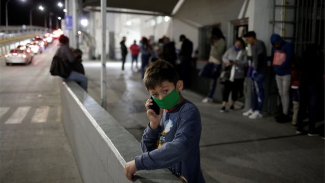 Un niño migrante habla por teléfono el 21 de abril en un paso fronterizo de México a EE.UU. mientras su familia hace la fila para reprogramar sus audiencias de casos de inmigración en EE.UU.