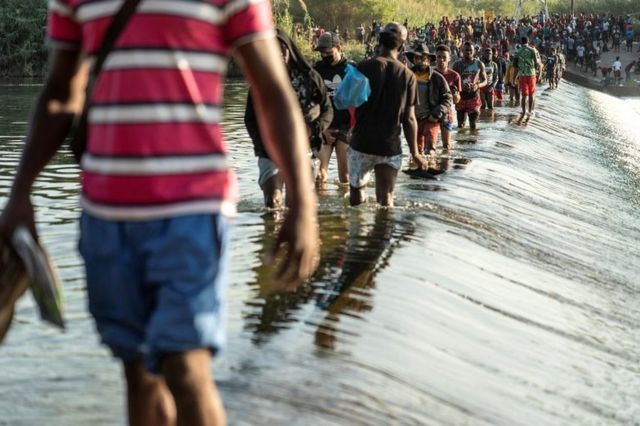 Migrantes que buscan asilo en Estados Unidos caminan por el río Grande cerca del Puente Internacional entre México y Estados Unidos, mientras esperan ser procesados, en Ciudad Acuña, México, el 16 de septiembre de 2021.