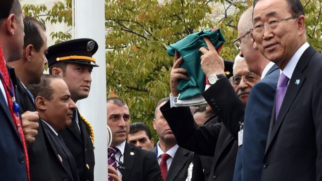 Mahmoud Abbas raises a folded Palestinian flag at UN headquarters in New York (30 September 2015)