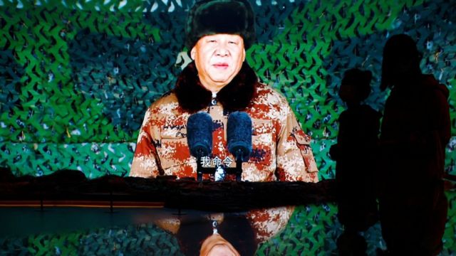 Visitors walk past a giant screen displaying Chinese President Xi Jinping delivering a speech to members of the Chinese People"s Liberation Army (PLA), at an exhibition at the Military Museum of the Chinese People"s Revolution in Beijing, China October 8, 2022