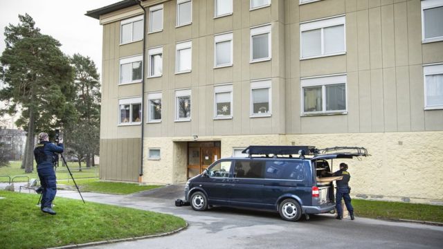 Police officers near the building that houses the apartment