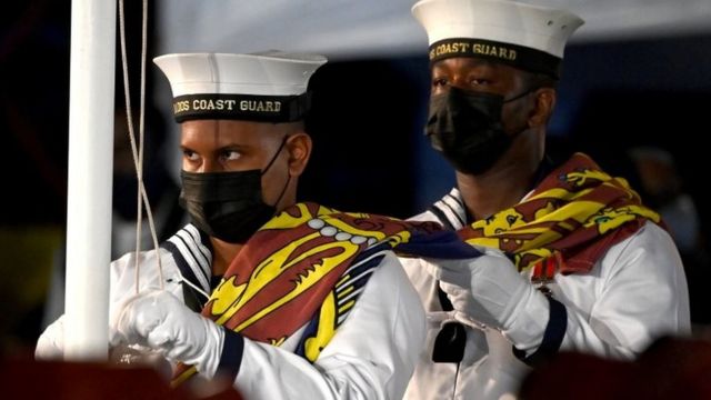 Members of the Barbados Coast Guard remove the flag from the Queen's royal standard