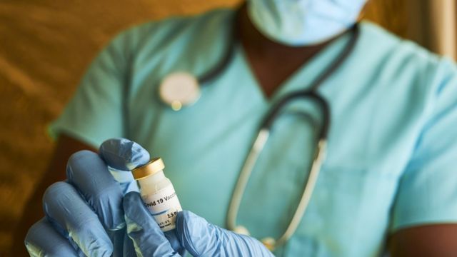 Afrykański lekarz trzyma butelkę szczepionki Covid.