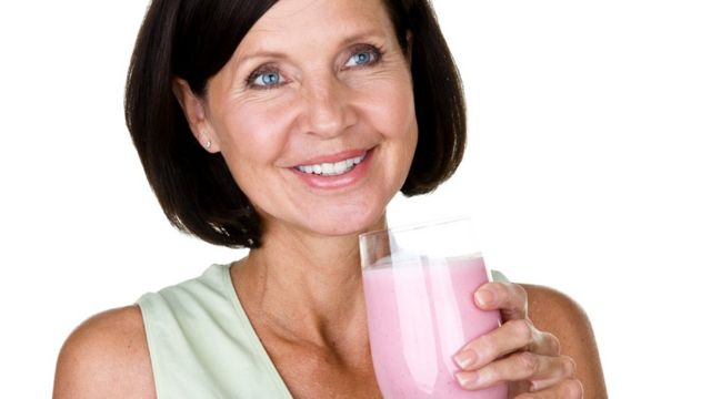 Older woman holding a glass of strawberry-flavoured drink
