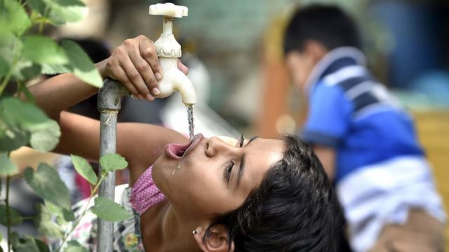 A girl quenching her thirst from a water tap in New Delhi, India