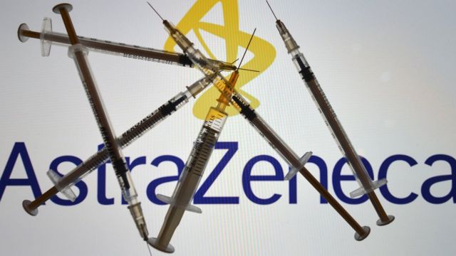 Jeringas con el logo de AstraZeneca de fondo.