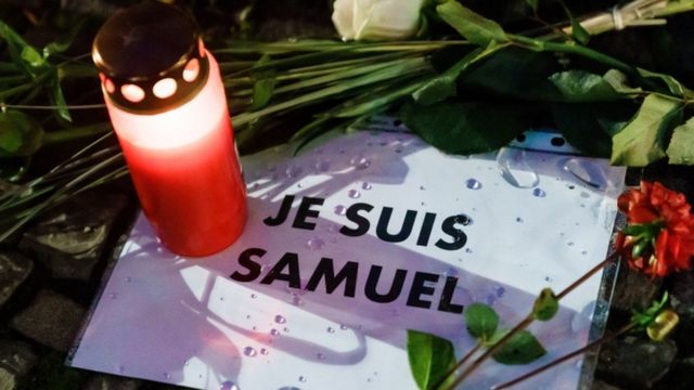 A candle and flowers are left next to a message in French that says: 