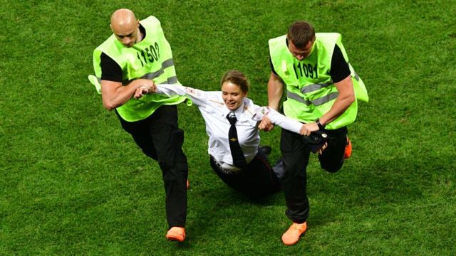 Una joven es llevada a rastras por guardias de seguridad tras invadir el campo durante la final del Mundial en Rusia.