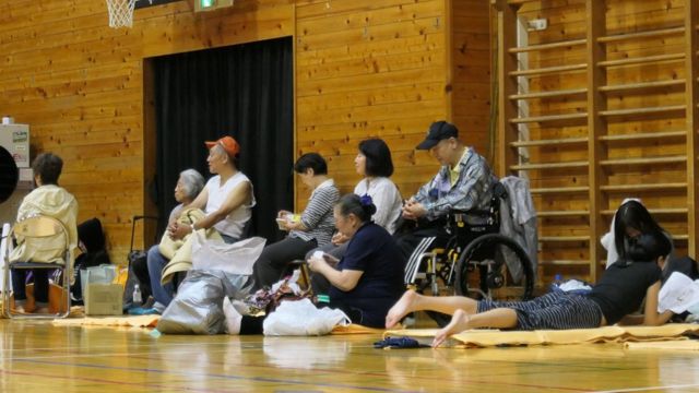 Evacuated residents sit inside a shelter to wait out the storm in Tokyo on 12 October 2019.