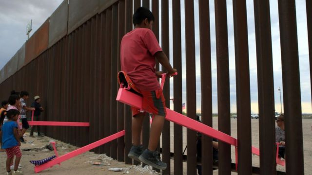 Los niños juegan en columpios en la pared en la frontera México-Estados Unidos
