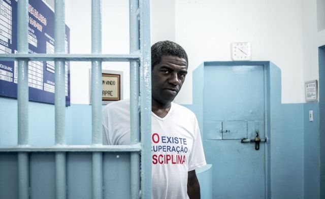 رجل يقف خلف أسوار في مؤسسة لإعادة تأهيل المجرمين في البرازيل.