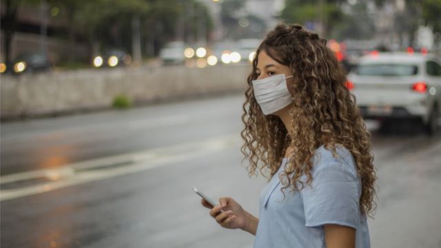 Mulher usando máscara em rua de São Paulo