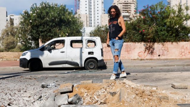一名以色列妇女正在查看地面上的加沙火箭残骸。