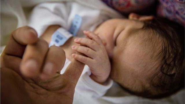 bebe recién nacido toma mano de su madre