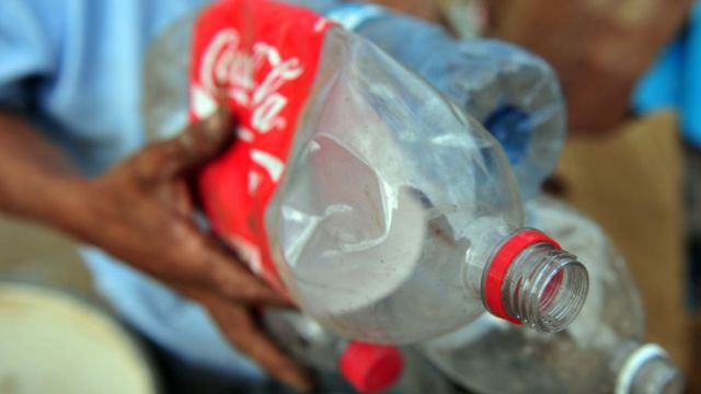 Un hombre reciclando botellas de plástico de Coca-Cola