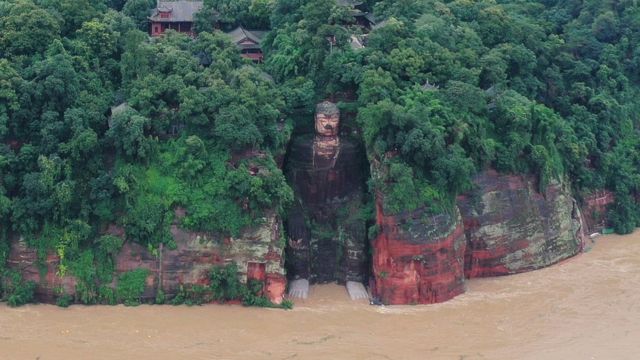 Giant Buddha carved from rock with floodwater around its base (18 Aug)