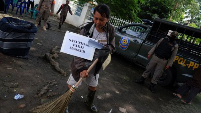 Seorang warga pelanggar protokol kesehatan menyapu jalan usai mengikuti sidang Operasi Yustisi, di Medan, Sumatera Utara, Selasa (15/09).
