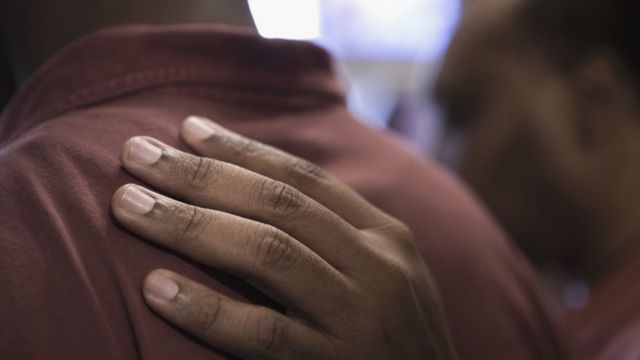 Una mano de un hombre en la espalda de otro en señal de apoyo.