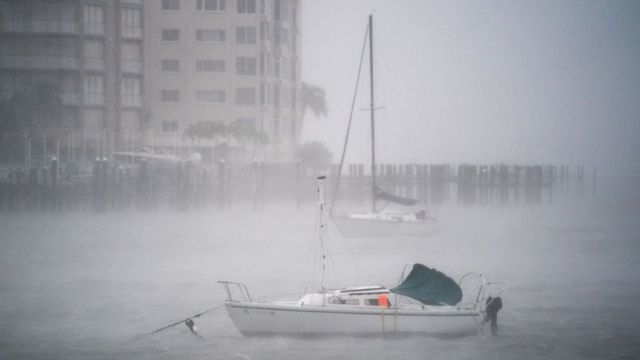 Boat in the middle of a marina, barely visible due to the mist caused by strong wind and rain.