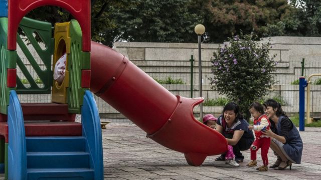 Pyongyang'da bir parkta çocuklar, anneleriyle birlikte oynuyor.