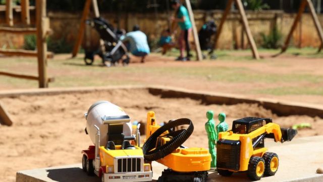 Carrinhos de brinquedo em primeiro plano e família se divertindo em parque