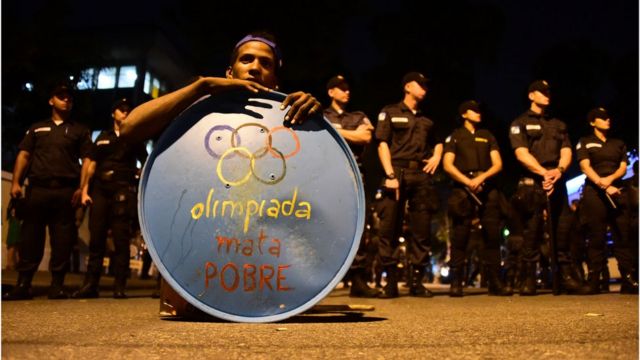 Un hombre con un letrero que dice "Olimpiada mata pobre" protesta contra las olimpiadas de Río 2016.