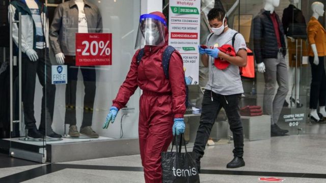 A woman wearing a biosafety suit walks holding a shopping bag at the Unicentro shopping center in Bogota, Colombia on July 01, 2020.