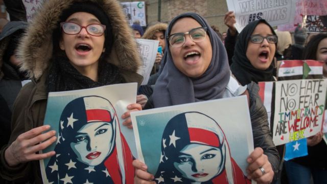 Three Muslim women protest Donald Trump's immigration order.