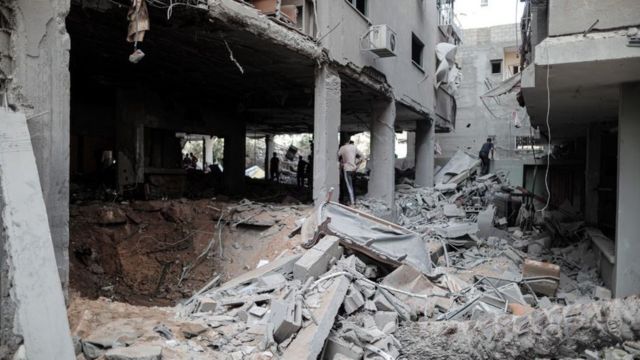 Pessoas inspecionam os escombros de um edifício residencial que foi atingido por ataques aéreos israelenses na Cidade de Gaza