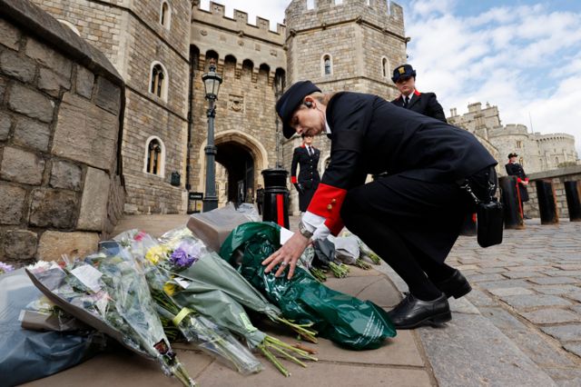 Wardens of the Castle move floral tributes to the side of the driveway at the Henry VIII Gate of Windsor Castle