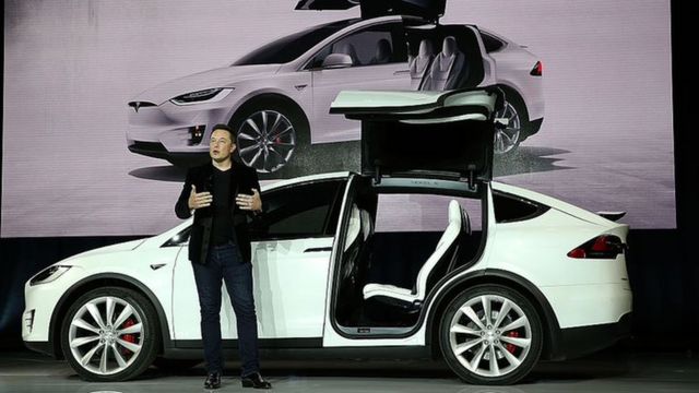Elon Musk al lado de un vehículo eléctrico Tesla.