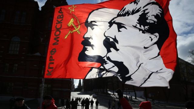 Một nhà hoạt động thuộc Đảng Cộng sản Nga giơ cao lá cờ có chân dung của hai nhà lãnh đạo quân sự và chính trị của Liên Xô là Joseph Stalin và Vladimir Ilʹich Lenin vào ngày 05 tháng 03 năm 2022