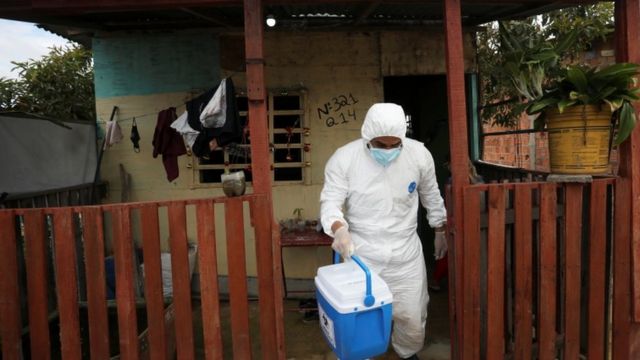 Profissional de saúde deixando casa após carregando cooler após examinar pessoa que morreu com suspeita de covid em Manaus