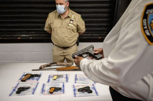 ضباط يعرضون الأسلحة المُصادرة من شوارع مدينة نيويورك